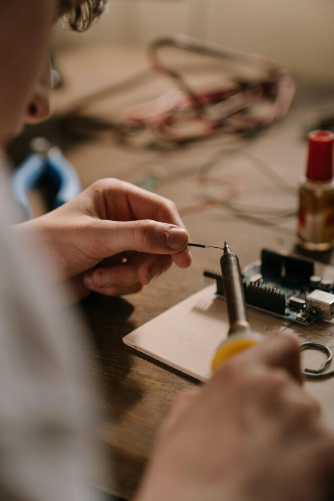 A person using a soldering iron to work on a circuit board, focused on precise electronic repair.